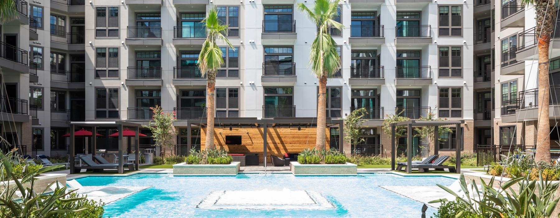 a large white building with palm trees and a pool in front of it