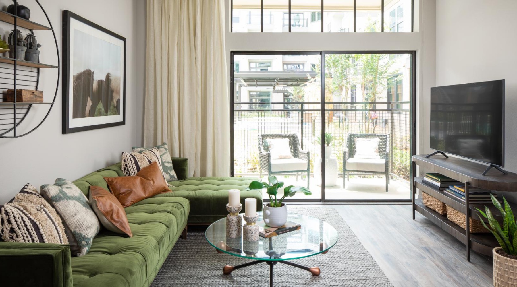 a living room with a green couch and large glass balcony door