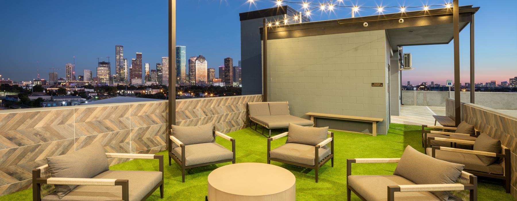 a rooftop patio with chairs and a large city in the background
